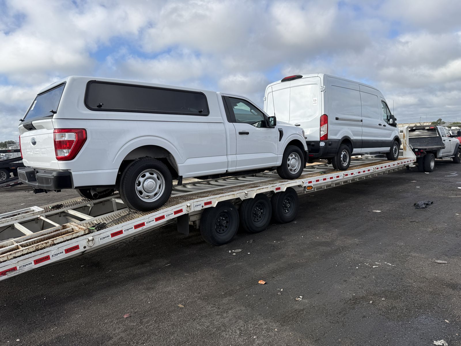 White Ford F-150 and Ford Transit van on the car trailer