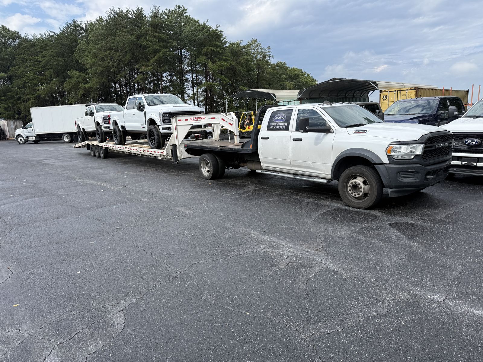 White Ram dually with Gorilla decal pulling a gooseneck car trailer loaded with two white Ford Super Duty trucks